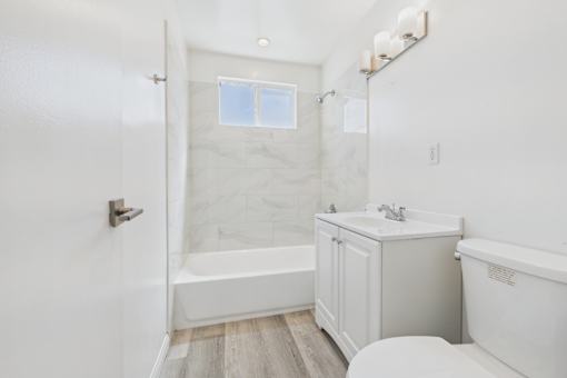 A white bathroom with a tub, sink, and toilet.