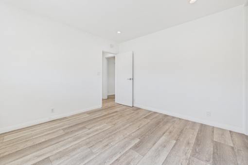 A room with wooden flooring and white walls.