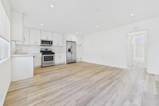 A kitchen with white cabinets and a wooden floor.