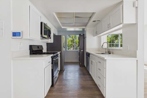 A modern kitchen with white cabinets and appliances.