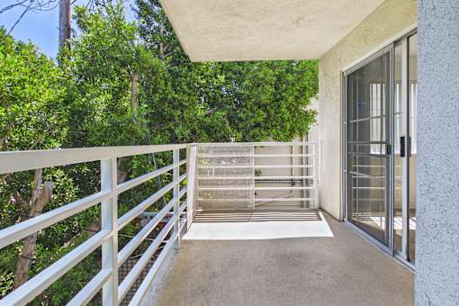 A balcony with a metal railing and a glass door leading to a patio.