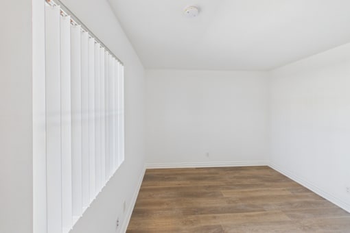 A room with wooden flooring and white walls.