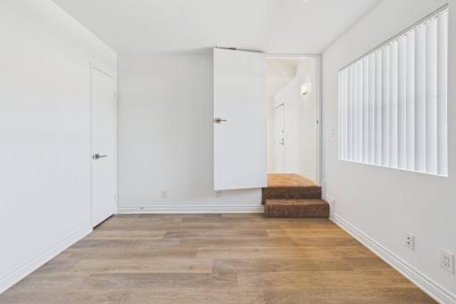 A room with wooden flooring and white walls.