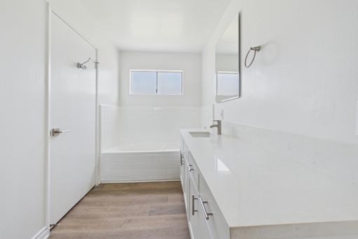 A white bathroom with a tub, sink, and mirror.