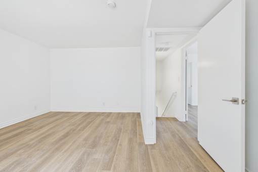 A room with wooden flooring and white walls.