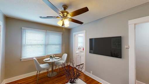 A dining room with a table and chairs and a ceiling fan.