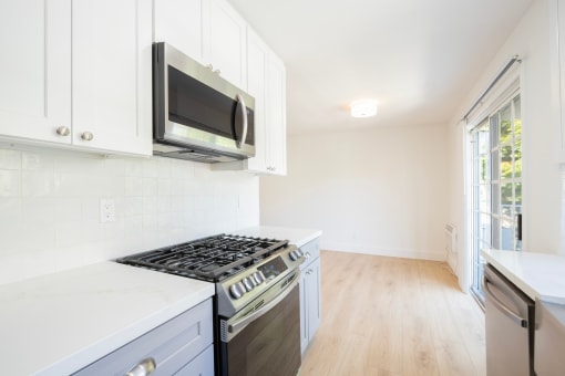 a kitchen with white cabinets and a stove and a microwave