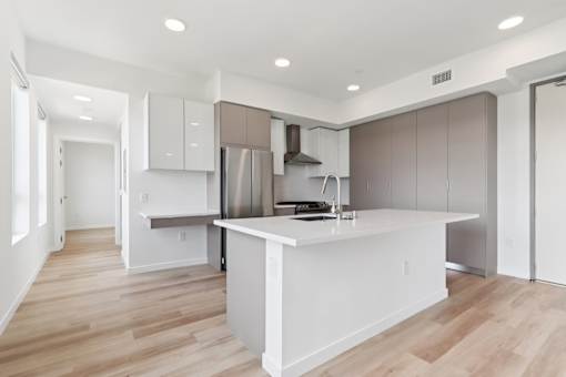 A modern kitchen with a white island and wooden floors.