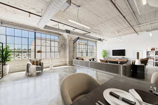 A modern living room with a large window and a grey couch.