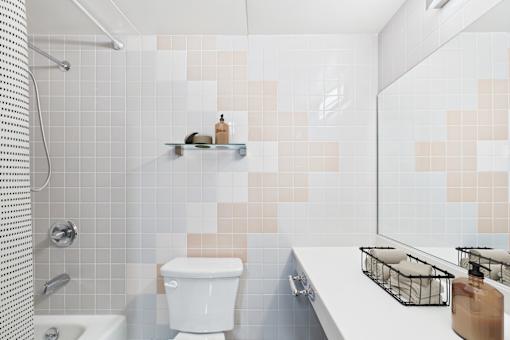 A white toilet sits in a bathroom with a shower and a sink.