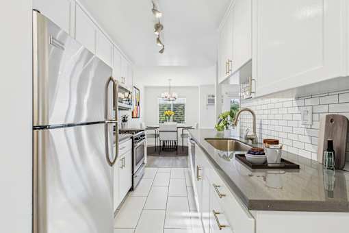 A kitchen with a stainless steel refrigerator and white cabinets.