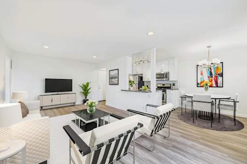 A modern living room with a television, a coffee table, and a dining table.
