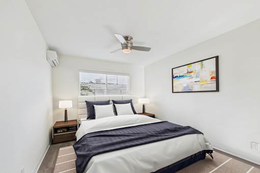 A bedroom with a bed, nightstands, and a ceiling fan.
