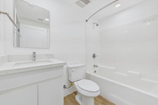 A white bathroom with a toilet, sink, and bathtub.