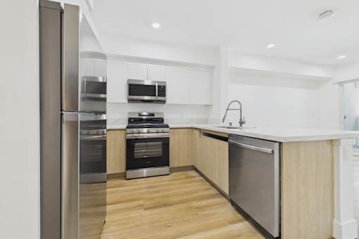 A modern kitchen with stainless steel appliances and wooden flooring.