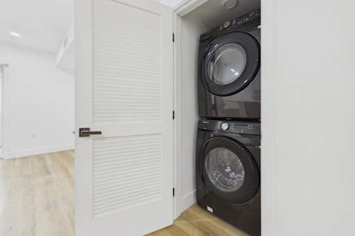 A black washing machine is in a white cabinet.