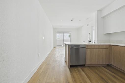 A kitchen with a white counter top and wooden floors.