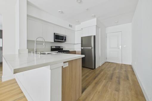 A modern kitchen with a white countertop and stainless steel appliances.