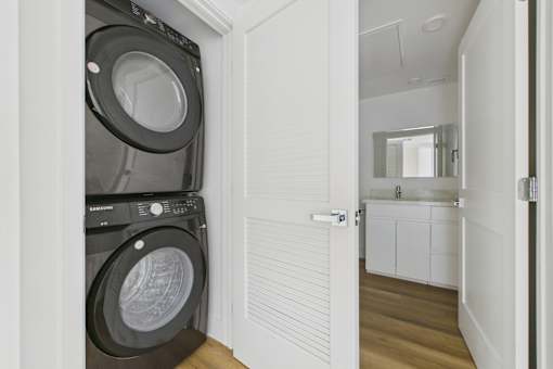A black washing machine is in a white doorway.
