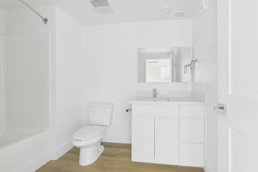 A white bathroom with a toilet, sink, and mirror.
