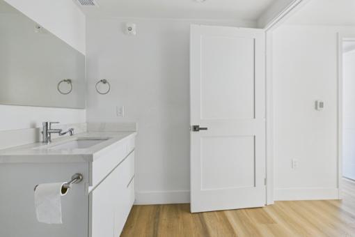 A white bathroom with a sink and mirror.