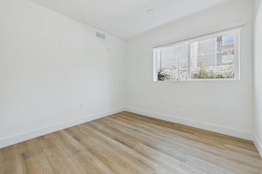 Empty room with a window and wooden flooring.
