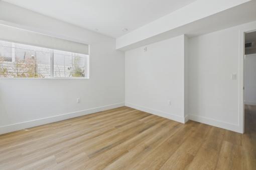 A room with wooden flooring and white walls.