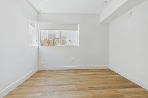 Empty room with wooden flooring and white walls.