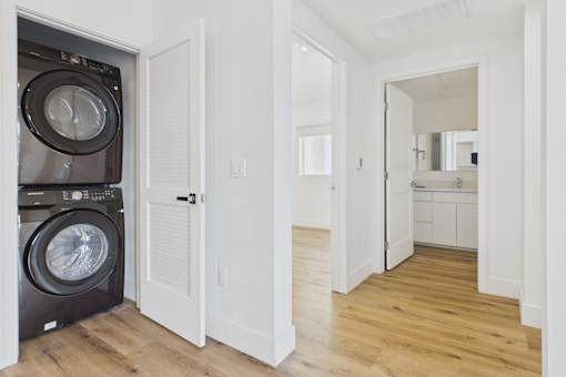 A black front-loading washing machine is in a white laundry room.