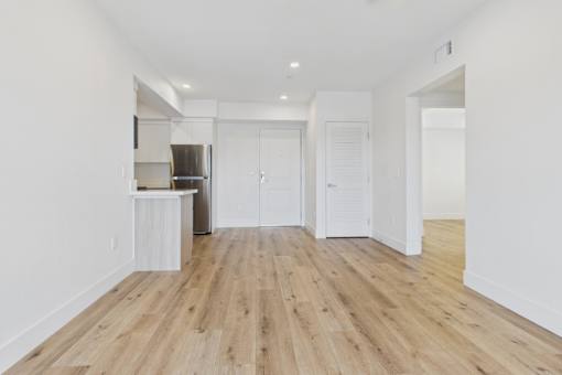A spacious room with wooden flooring and white walls.