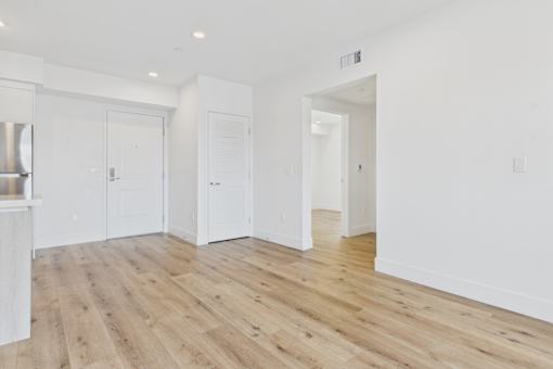 A white room with wooden floors and three white doors.