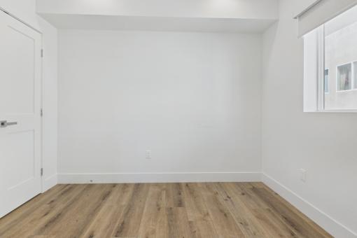 A room with wooden flooring and white walls.