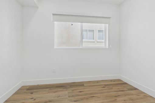 A room with a window and wooden flooring.