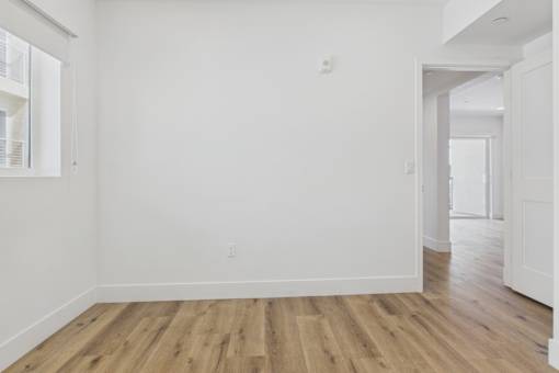 A room with wooden flooring and white walls.