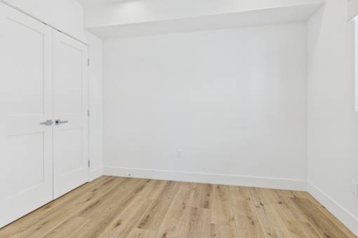A room with a white door and wooden flooring.