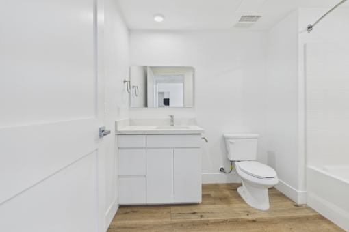 A white bathroom with a toilet, sink, and mirror.