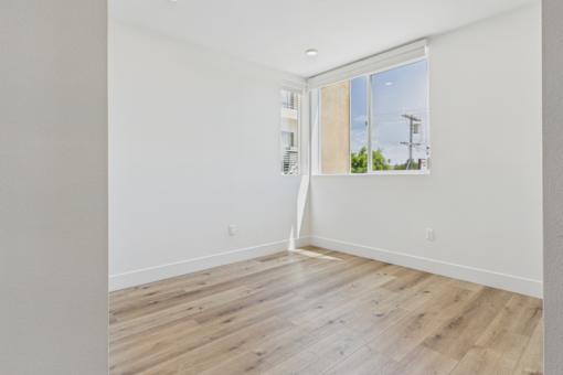 A room with wooden flooring and a window overlooking a street.
