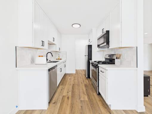 A kitchen with white cabinets and black appliances.