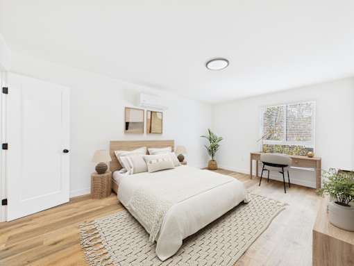 A bedroom with a large bed and a small desk with a chair.