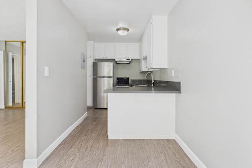 A kitchen with white cabinets and a wooden floor.