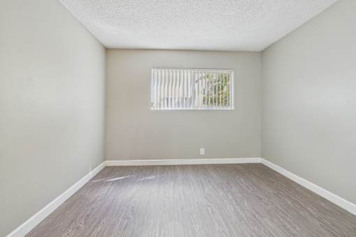 A room with a window and wooden flooring.