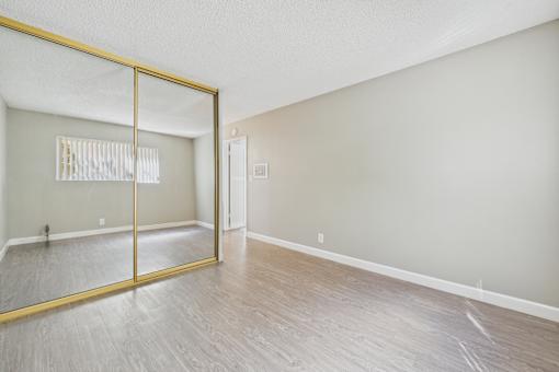 A room with a wooden floor and a large mirror on the wall.