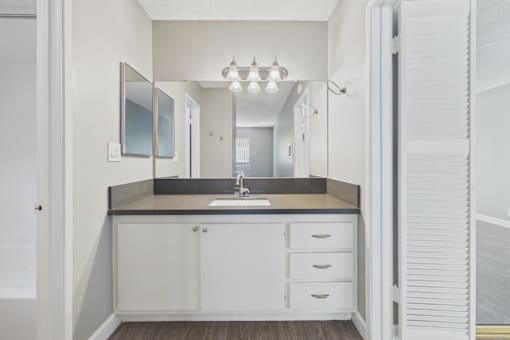 A bathroom with a sink, mirror, and cabinet.