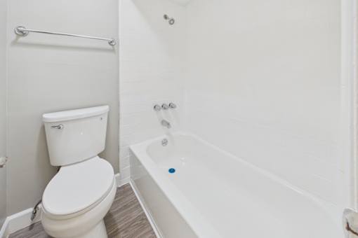 A white toilet sits next to a white bathtub in a bathroom.