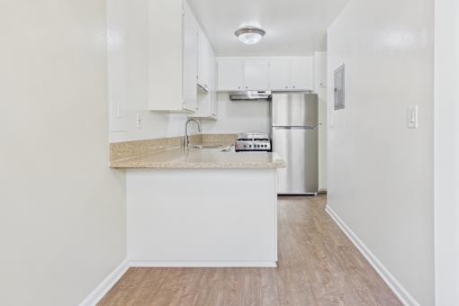 A kitchen with white cabinets and a wooden floor.
