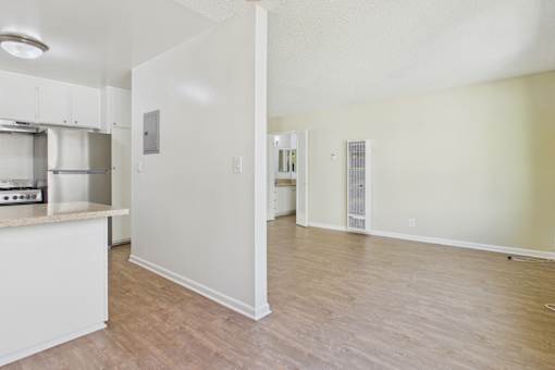 A kitchen with white cabinets and a wooden floor.