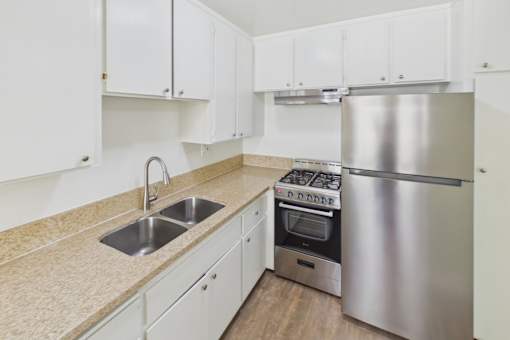 A kitchen with white cabinets and a stainless steel refrigerator.