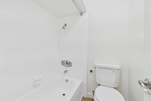 A white bathroom with a toilet, tub, and shower.