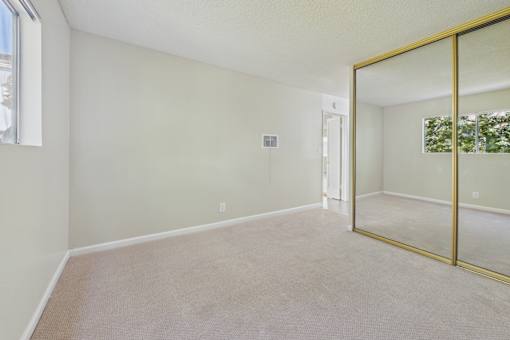A room with a carpet floor and a large mirror on the wall.