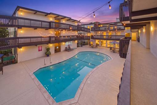 A large outdoor swimming pool surrounded by a patio area with lights strung above.